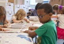 채플힐-캐보로 학군 예산 부족으로 5개 학교 폐교 검토 boy in green sweater writing on white paper