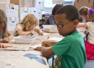 채플힐-캐보로 학군 예산 부족으로 5개 학교 폐교 검토 boy in green sweater writing on white paper